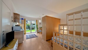 Een moderne kamer met een bed, een televisie, een bureau en een schuifdeur naar een balkon.