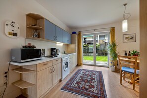 A compact kitchen with modern appliances, a dining area with a table and chairs, and a sliding glass door leading to a balcony.
