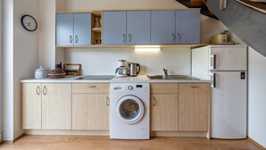 Une cuisine compacte équipée d’un lave-linge, d’une machine à café et d’un réfrigérateur.