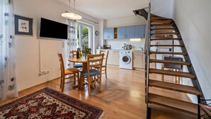 Une cuisine moderne avec des meubles en bois, un coin repas comprenant une table et des chaises, et un escalier.