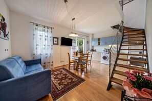Un salon moderne comprenant un canapé, une table à manger, des chaises, un escalier et un coin cuisine.