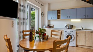 Une cuisine moderne équipée d’un lave-linge, d’une table à manger avec des chaises et d’un téléviseur fixé au mur.