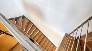 Un escalier en bois avec des rampes en métal et un mur blanc.