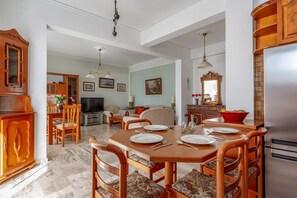 Un coin repas avec une table en bois dressée pour quatre personnes, entourée de chaises à motifs floraux.
