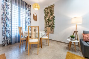 A dining area with a table and chairs, a lamp, and a wall with a plant.