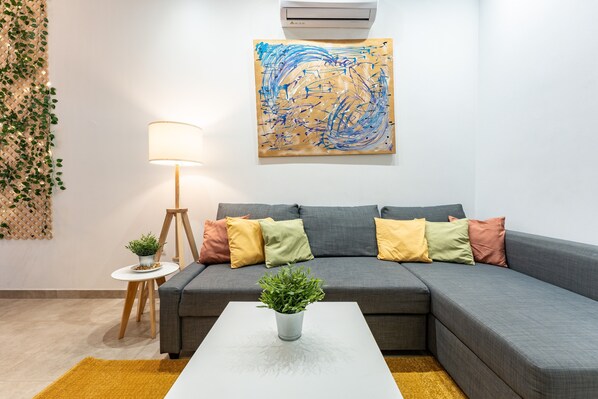 A living room with a gray sofa, a white coffee table, a floor lamp, and a painting on the wall.