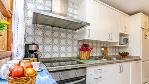 A kitchen with white cabinets, a stainless steel range hood, a microwave, and a sink. - Holiday Home 'Puig' with Mountain View, Wi-Fi and Air Conditioning (Pollensa)