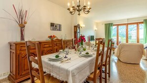 A dining area with a chandelier, wooden furniture, and a view of the outdoors. - Holiday Home 'Puig' with Mountain View, Wi-Fi and Air Conditioning (Pollensa)