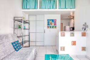 A modern living room with a sofa, a glass shelving unit, and a door leading to a kitchen. - Holiday Home 'Maisonnette 37 m²' with Private Terrace and Wi-Fi (LATTES)