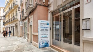 En gade med en bygning, der har et stort skilt med 'Investigaciones' og en butik med glasdøre.
