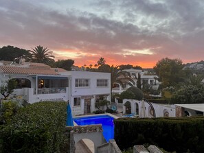 A residential area with a swimming pool, white buildings, and a sunset sky.