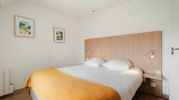 A bedroom with a bed, a headboard, a bedside table, and two framed pictures on the wall.