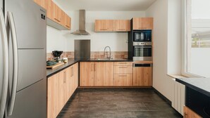 Eine moderne Küche mit Holzschränken, Edelstahlgeräten und einer schwarzen Arbeitsplatte.