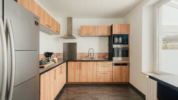 Une cuisine moderne avec des meubles en bois, des appareils en acier inoxydable et un plan de travail noir.