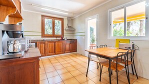 A kitchen with wooden cabinets, a stove, a sink, and a dining table with chairs.