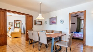 A dining area with a wooden table and chairs, a sofa, and a painting on the wall.