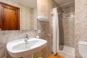 Un baño con lavamanos, espejo, ducha e inodoro.
