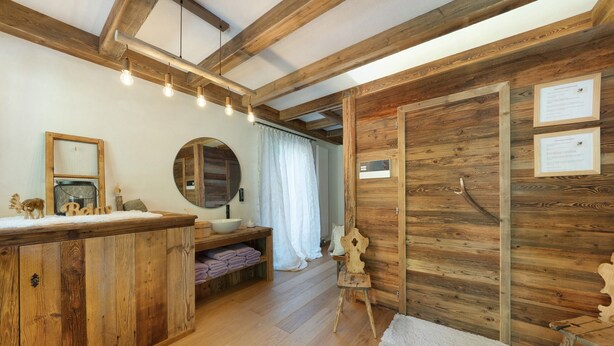 Un intérieur en bois avec un banc en bois, un miroir, un lavabo et un porte-serviettes.