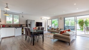 A modern kitchen with a dining area, a sofa, and a view of the outdoors.