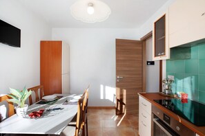 Una cocina moderna con un mueble de madera, un salpicadero de azulejos y una zona de comedor con una mesa preparada para dos.