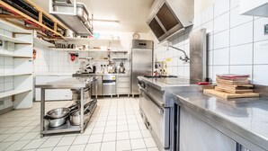 A modern kitchen with stainless steel appliances, white tiled walls, and a clean, organized layout.