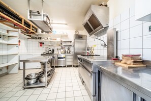 A modern kitchen with stainless steel appliances, white tiled walls, and a clean, organized layout.