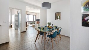 A dining area with a glass table, blue chairs, and a hanging light fixture. - Bella Vista Apartment in Premeno with Lake Maggiore View (Premeno)