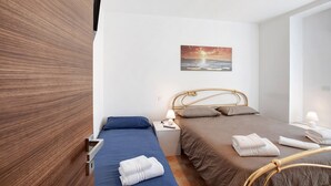 Habitació d'hotel amb dos llits, un quadre, un televisor i un armari de fusta.