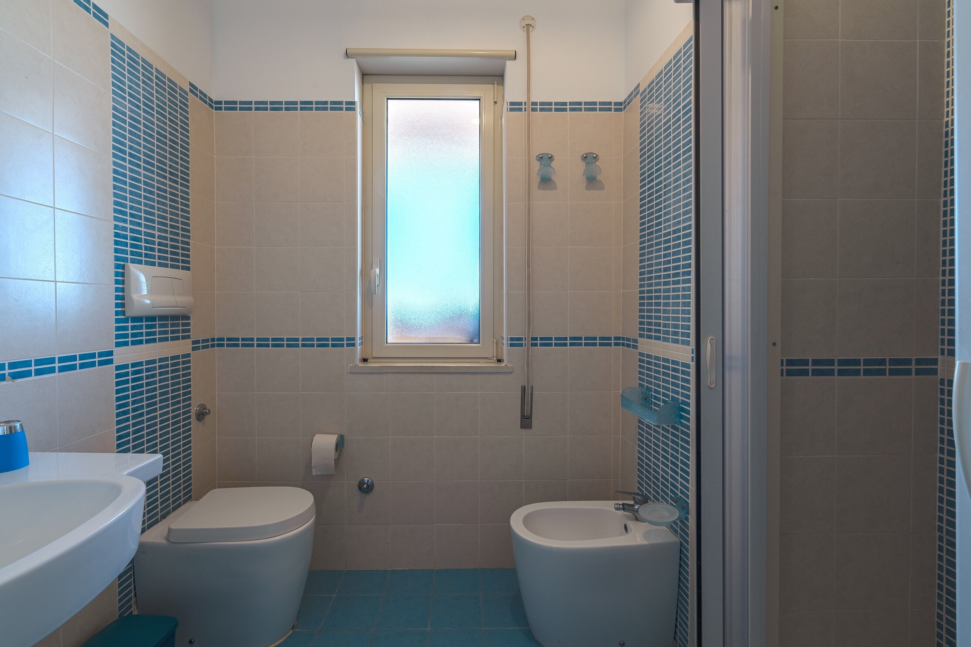 Ein Badezimmer mit zwei Toiletten, einem Waschbecken, einem Bidet und einer Dusche.
