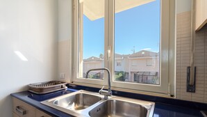 Una cocina con dos fregaderos, una ventana y vistas a edificios.