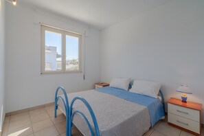 A bedroom with a bed, a nightstand, a lamp, a window, and a chair. - Holiday Apartment "Giulietta" with Sea View, Balcony & Wi-Fi (San Lorenzo)