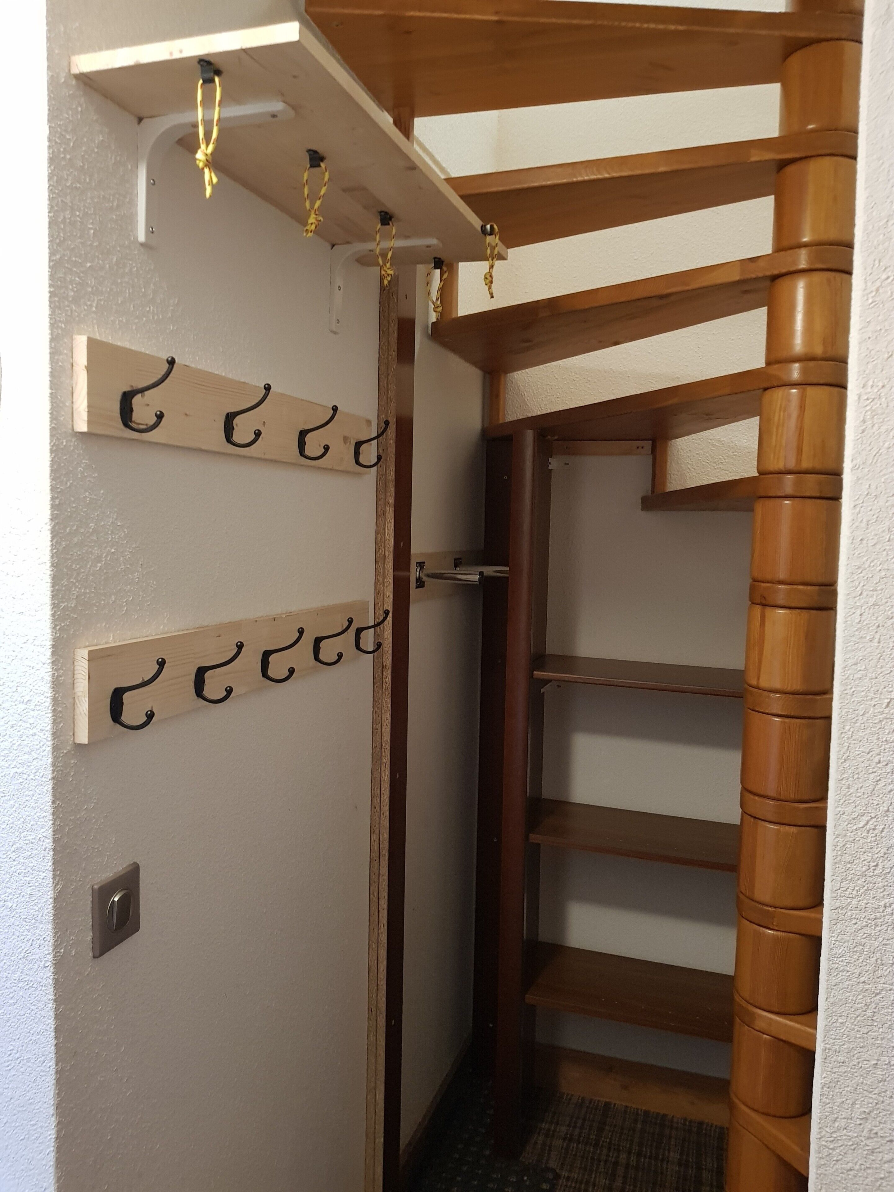 A wooden interior with a built-in shelf unit, a door with a metal handle, and a textured wall.