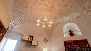 A room with a stone ceiling, a chandelier, a painting, and a shelf with books. - Apartment 'Casa Manca' with Private Terrace, Wi-Fi and Air Conditioning (Locorotondo)