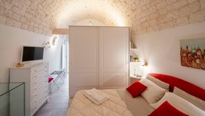 A bedroom with a bed, a wardrobe, a TV, and a painting on the wall. - Apartment 'Casa Manca' with Private Terrace, Wi-Fi and Air Conditioning (Locorotondo)