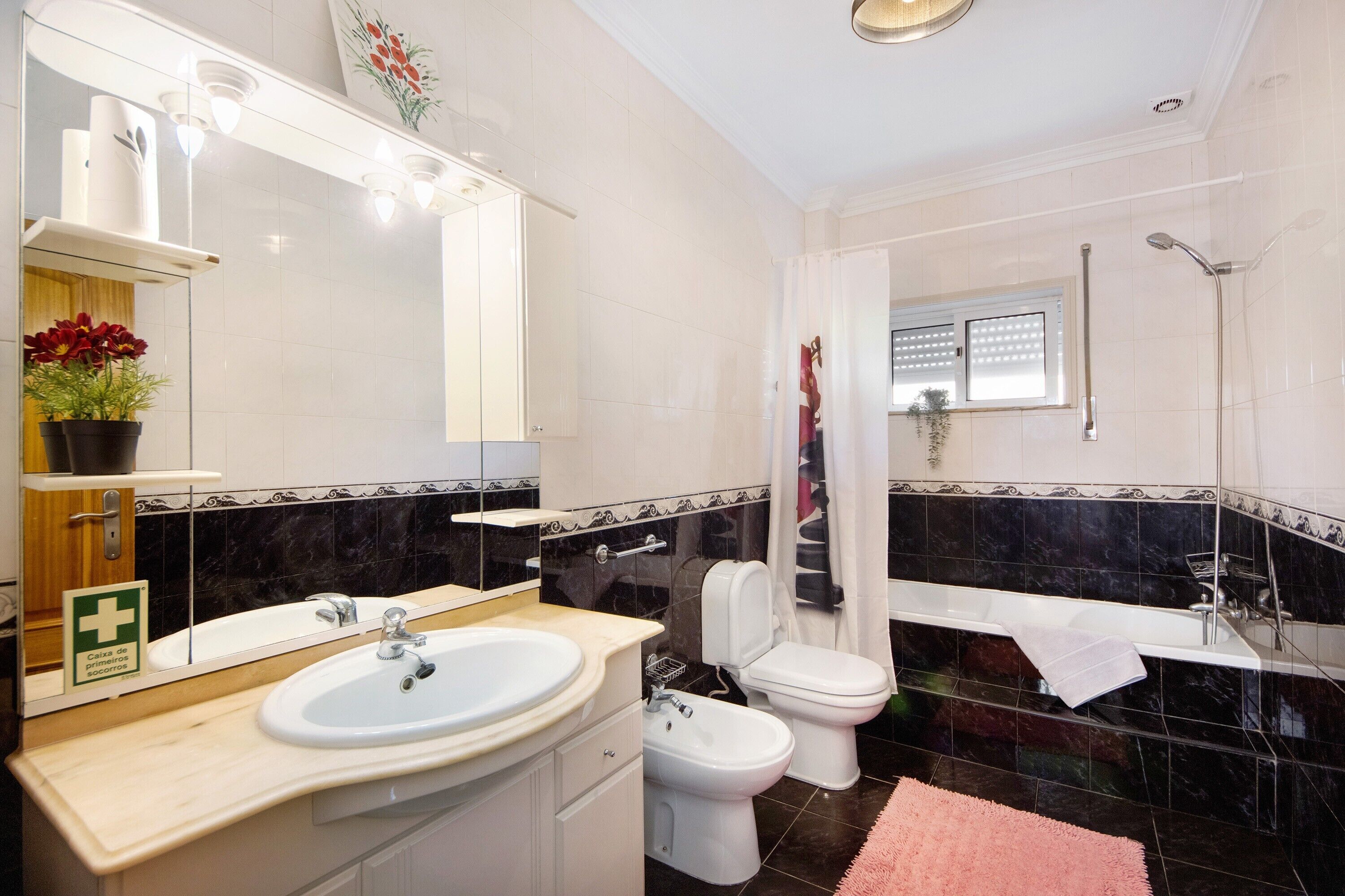A bathroom with a sink, toilet, bidet, and shower.