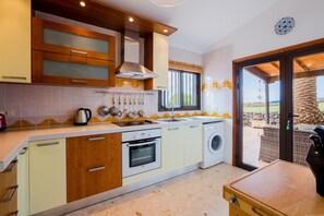 A modern kitchen with a built-in oven, a washing machine, and a large window.