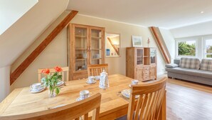 A dining area with a wooden table set for four, flanked by wooden cabinets and a sofa. - 3 bedroom gorgeous apartment in List (List)