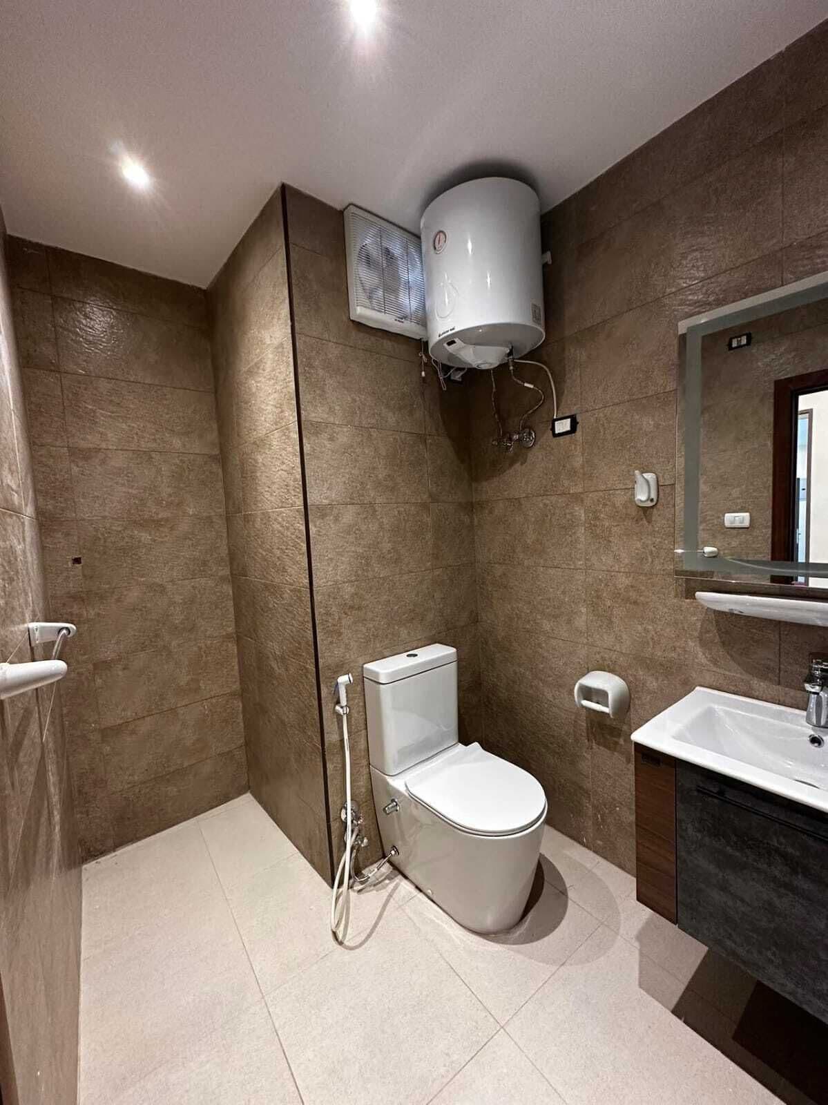 A modern bathroom with a toilet, shower, and sink.
