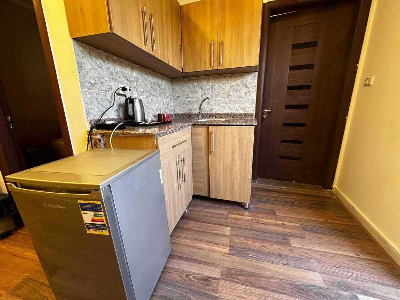 A compact kitchen with wooden cabinets, a built-in dishwasher, and a small refrigerator.