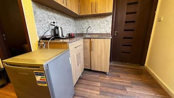 A compact kitchen with wooden cabinets, a built-in dishwasher, and a small refrigerator.
