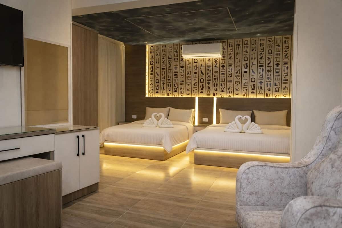 Une chambre d’hôtel avec deux lits, une télévision, un bureau et un mur orné de panneaux décoratifs.