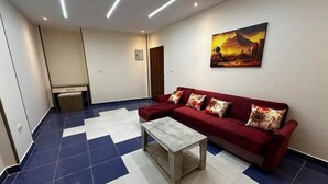 A modern living room with a red sofa, a marble coffee table, and a large painting on the wall. - Narmer Pyramids View (Giza)