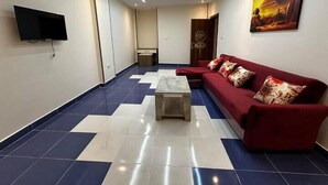 A spacious lobby with a red sofa, a coffee table, and a flat-screen TV mounted on the wall. - Narmer Pyramids View (Giza)