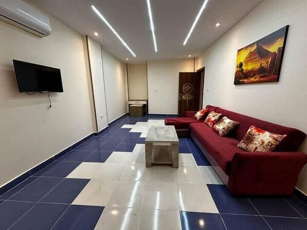 Un lobby amplio con un sofá rojo, una mesa de centro y un televisor de pantalla plana montado en la pared.