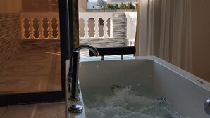 A modern bathroom with a bathtub, a shower, and a glass door leading to a balcony with a view of a pyramid and buildings. - Narmer Pyramids View (Giza)