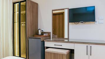 Una habitación de hotel con cama, minibar, televisor y espejo.