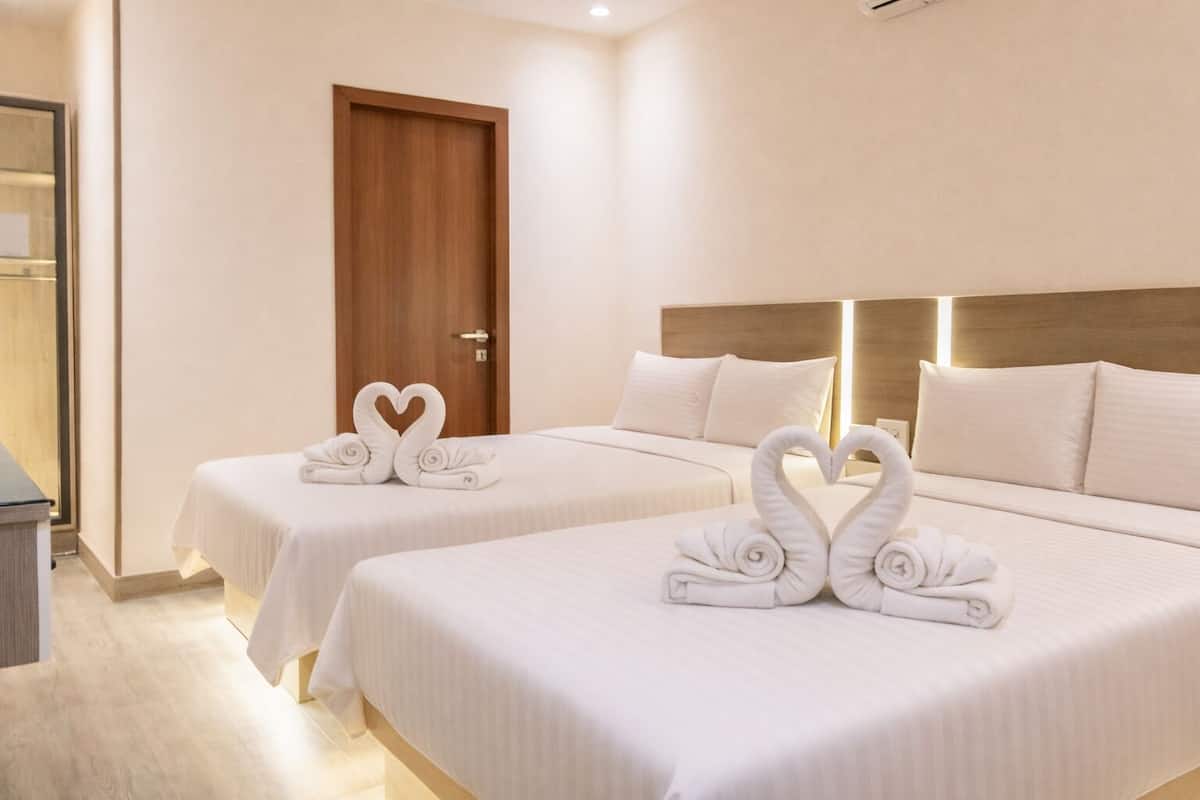 Une chambre d’hôtel avec deux lits, une porte en bois et une table de chevet.
