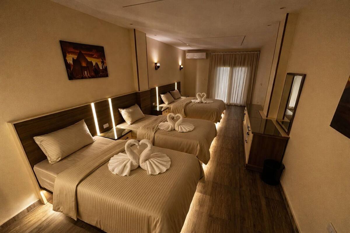Une chambre d’hôtel avec deux lits, chacun agrémenté d’une décoration en forme de cœur faite avec des serviettes, un tableau au mur et un grand miroir.