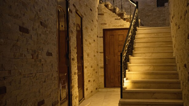 A staircase leading up to a door with a metal railing, surrounded by stone walls and a tiled floor. - Narmer Pyramids View (Giza)