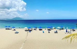 A beach with sun loungers and umbrellas, a clear sky, and a calm sea. - Spacious beautiful villa 5 minutes from Sosua night live and 10 from Cabarete.  (Sosúa)